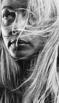 Captivating monochrome close-up of a woman with windswept blonde hair.