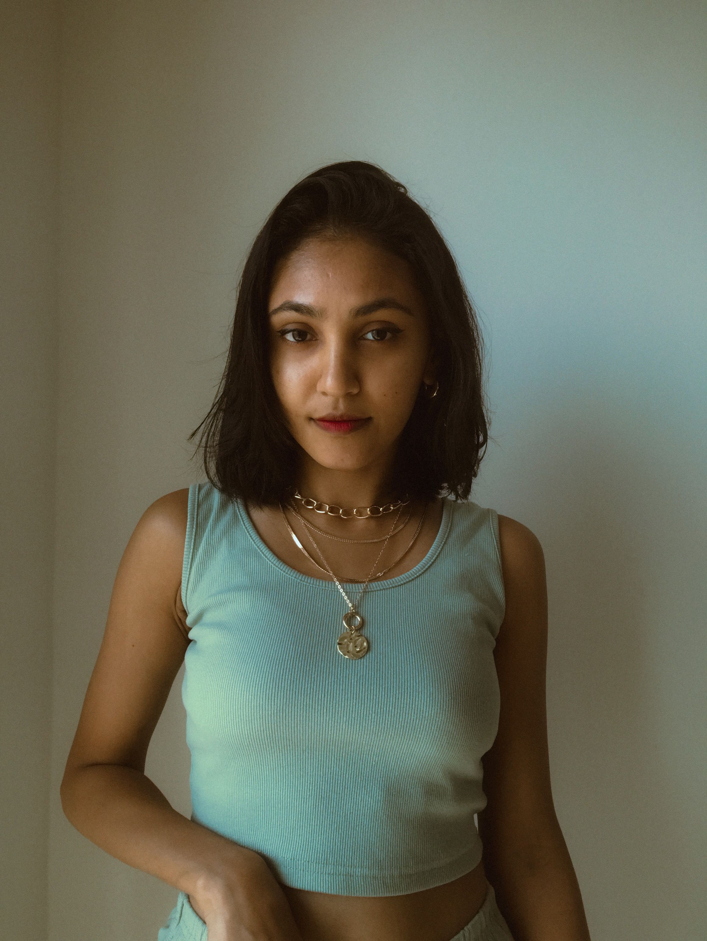 Brunette Woman with Necklaces Posing by White Wall · Free Stock Photo