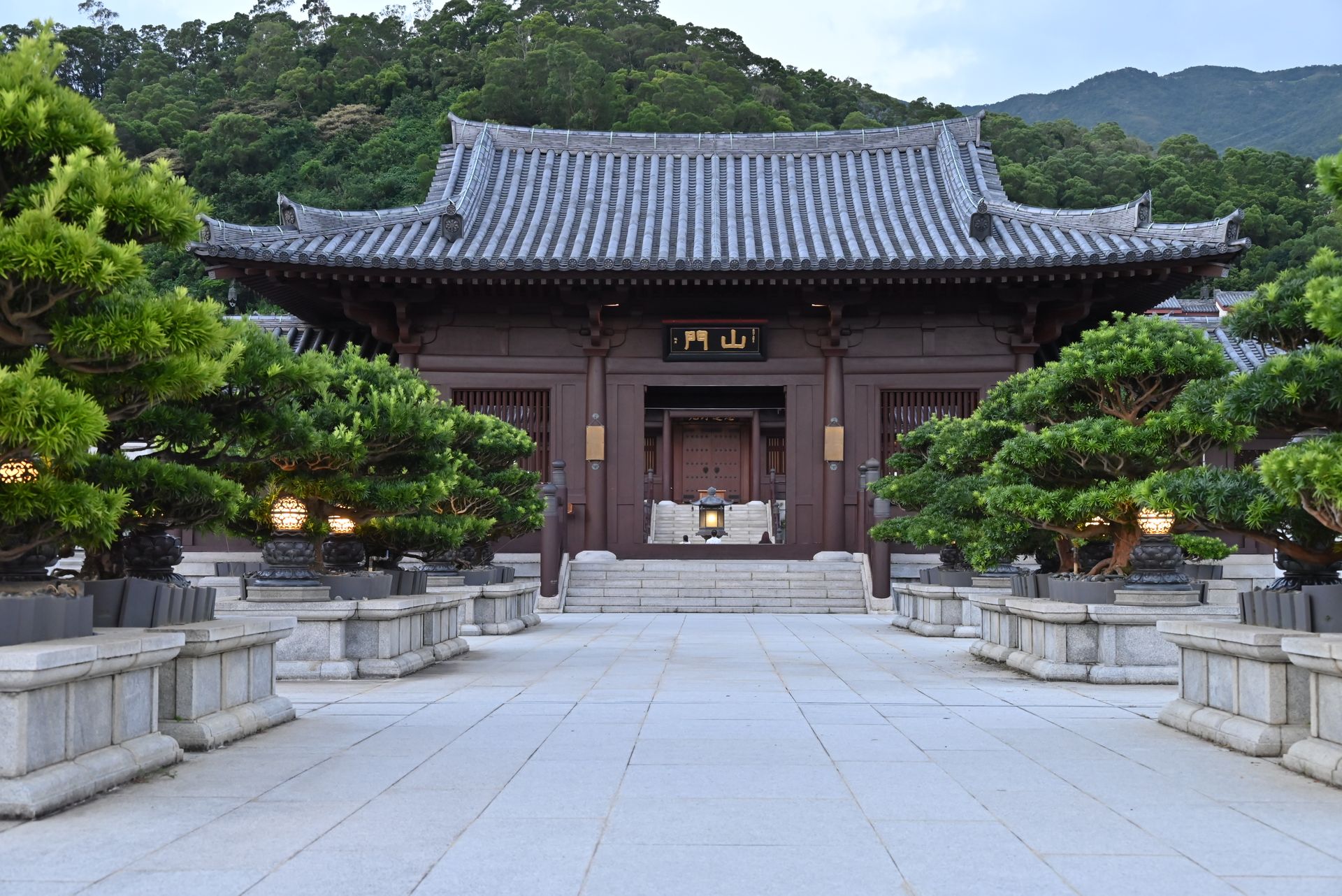 Serene view of Chi Lin Nunnery temple in Hong Kong, surrounded by lush bonsai trees, representing Zen tranquility.