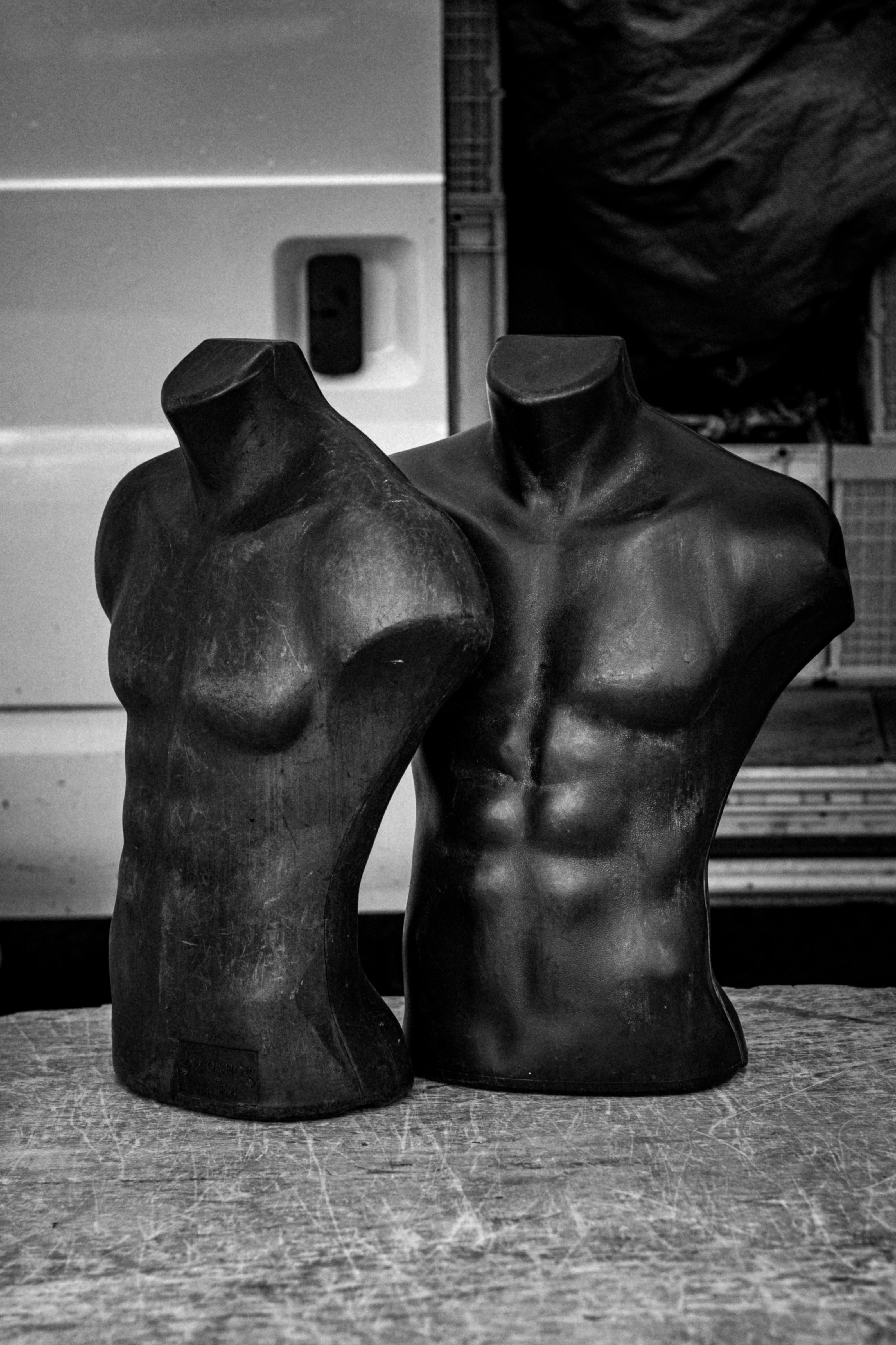 Artistic black and white photo of muscular torso mannequins outdoors.