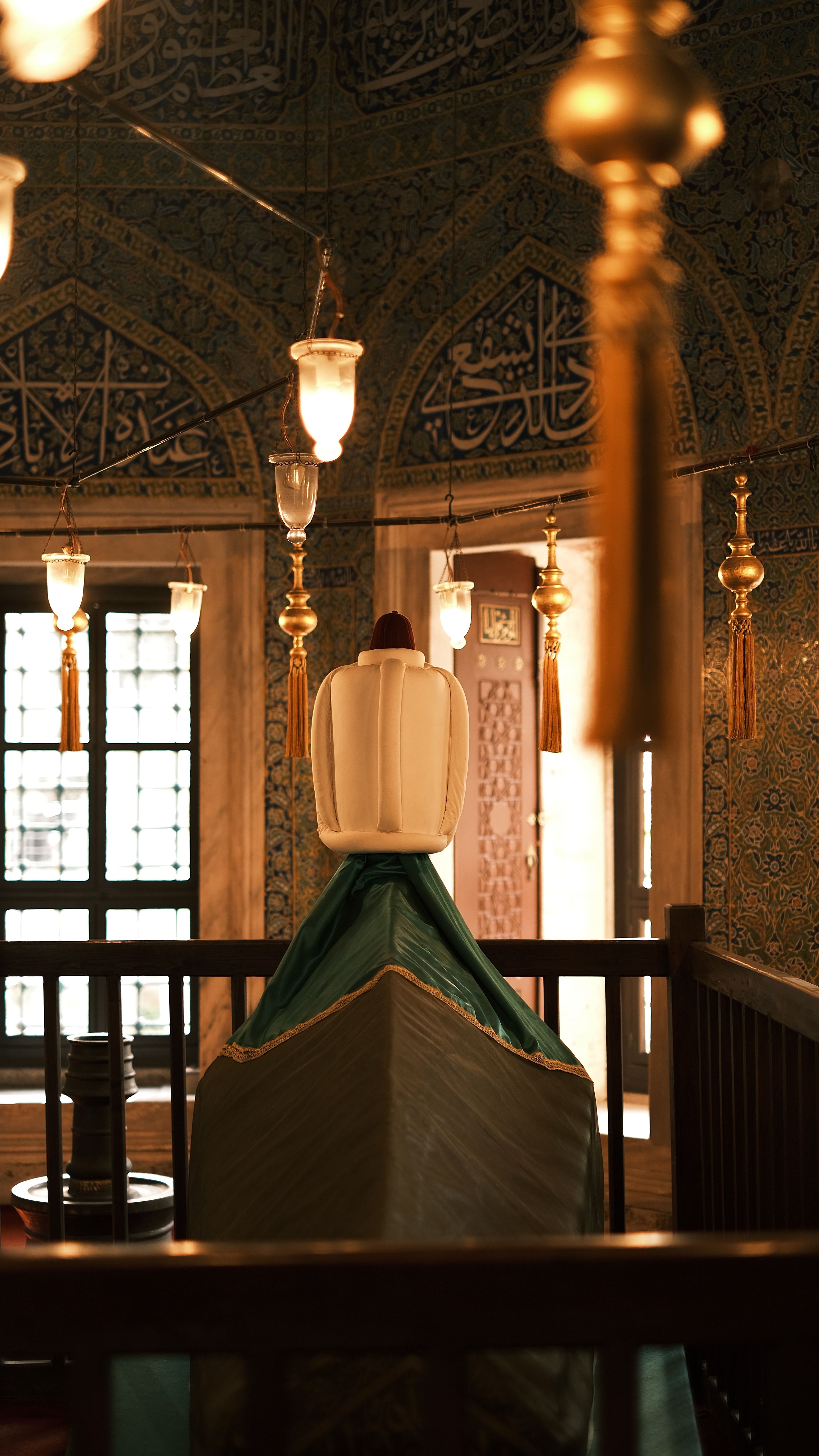 Beautifully ornamented interior of a mosque with Islamic calligraphy and hanging lamps.