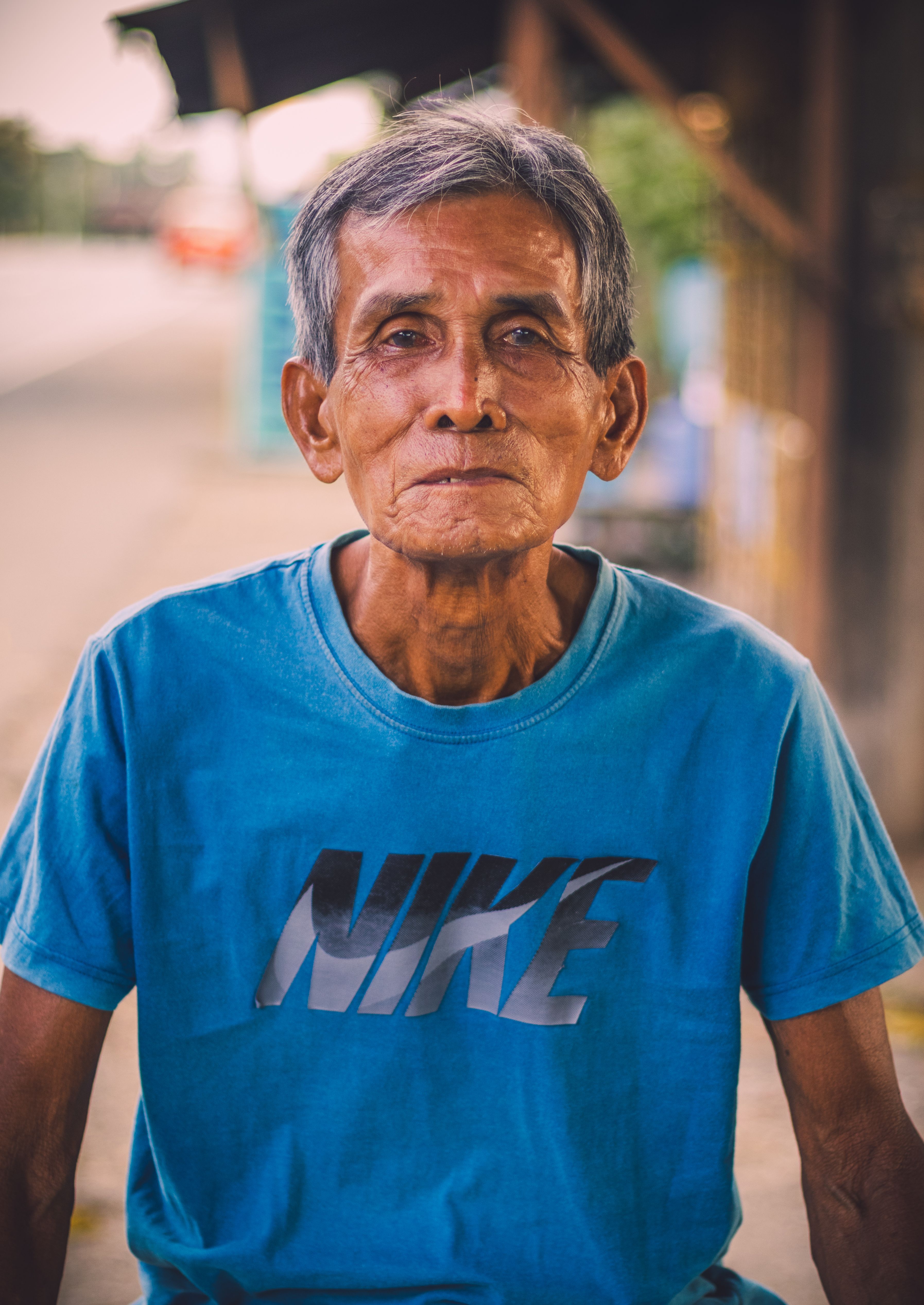 Portrait of an elderly man wearing a blue t-shirt, captured outdoors in Butuan City, Philippines.