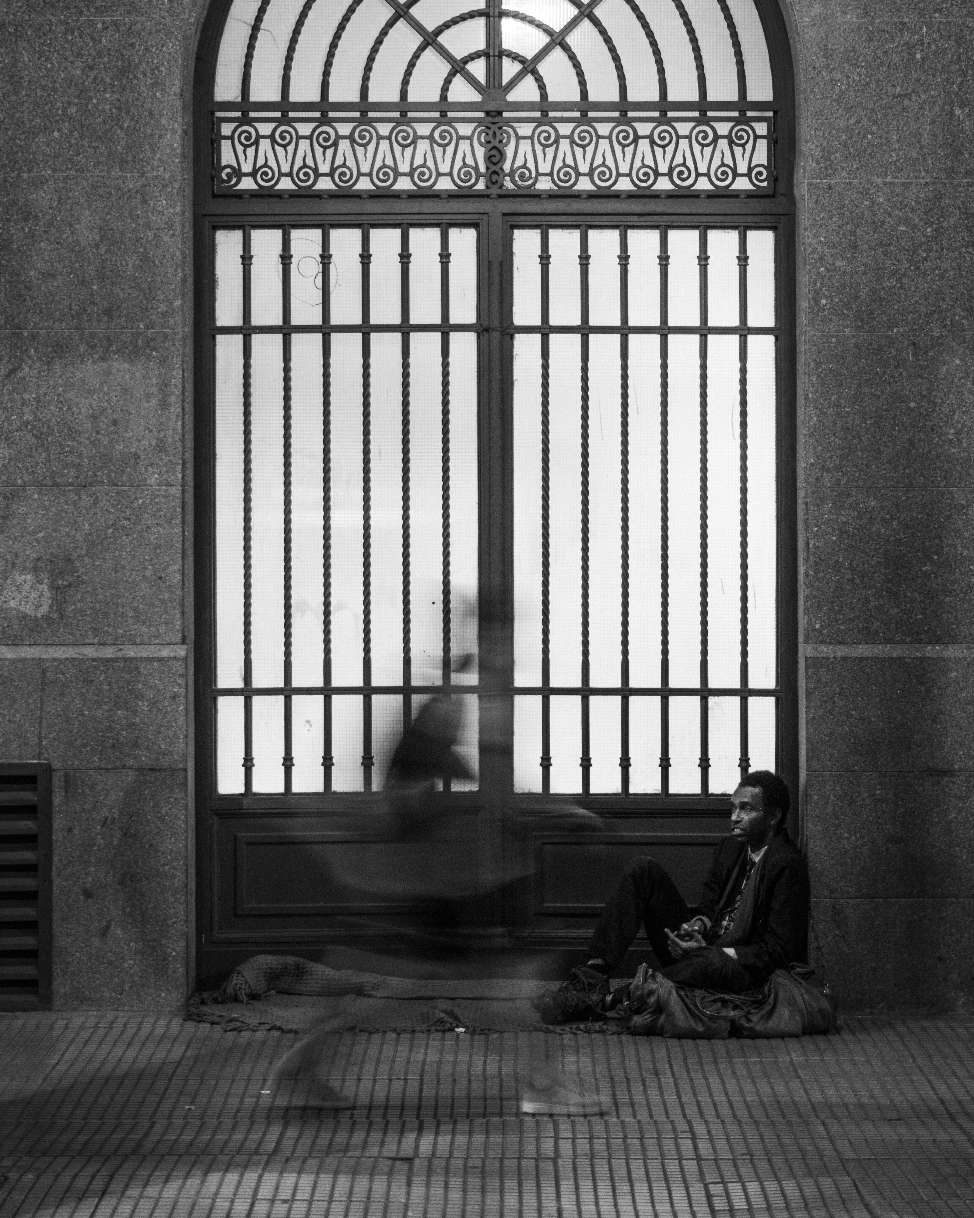 A person sitting on the ground in front of a window · Free Stock Photo