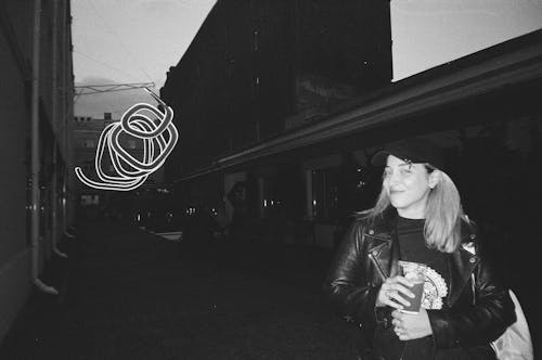 Smiling Woman in Cap and Jacket in Alley in Town in Black and White