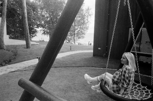 Woman Sitting on Swing in Park in Black and White