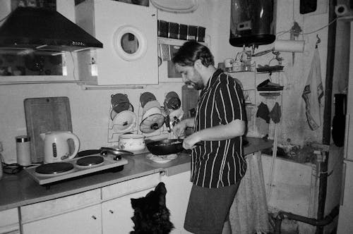 Man in Shirt Cooking in Kitchen in Black and White