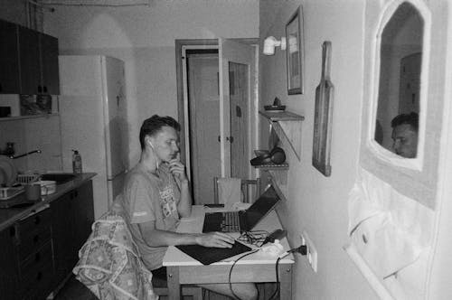 Man Sitting with Laptop in Kitchen