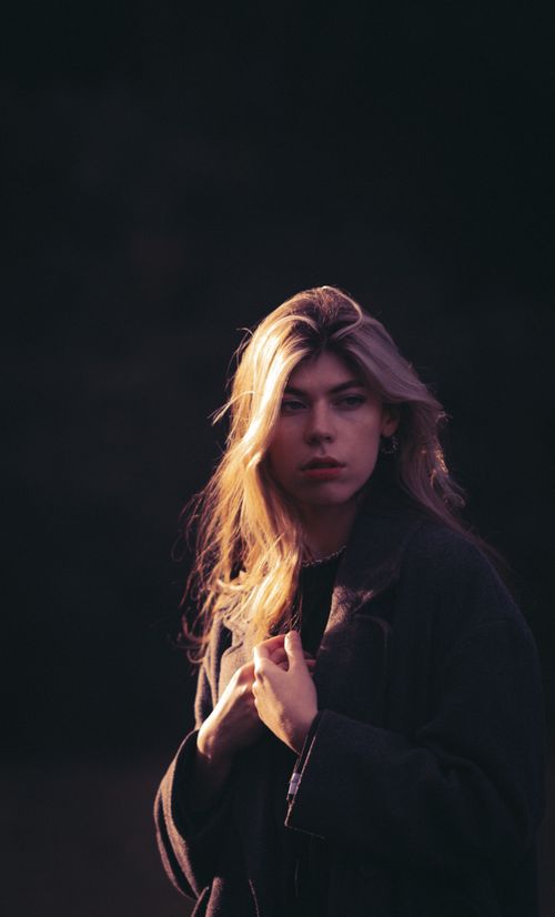 Free A striking portrait of a blonde woman captured in outdoor lighting, exuding a moody ambiance. Stock Photo
