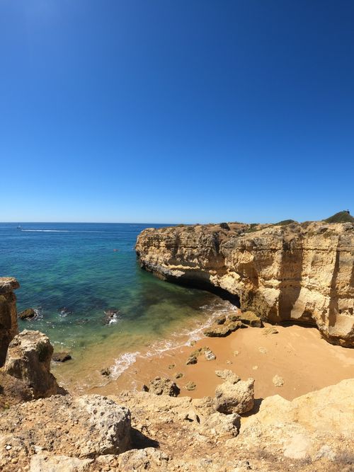 Free Beautiful coastal landscape featuring eroded cliffs and a sandy beach under a clear sky. Stock Photo