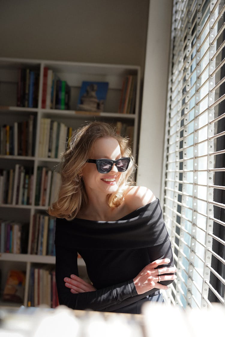 Smiling Woman In Sunglasses By Window With Blinds