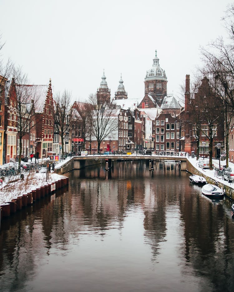 Canal In Amsterdam With The Basilica Of Saint Nicholas In The Background