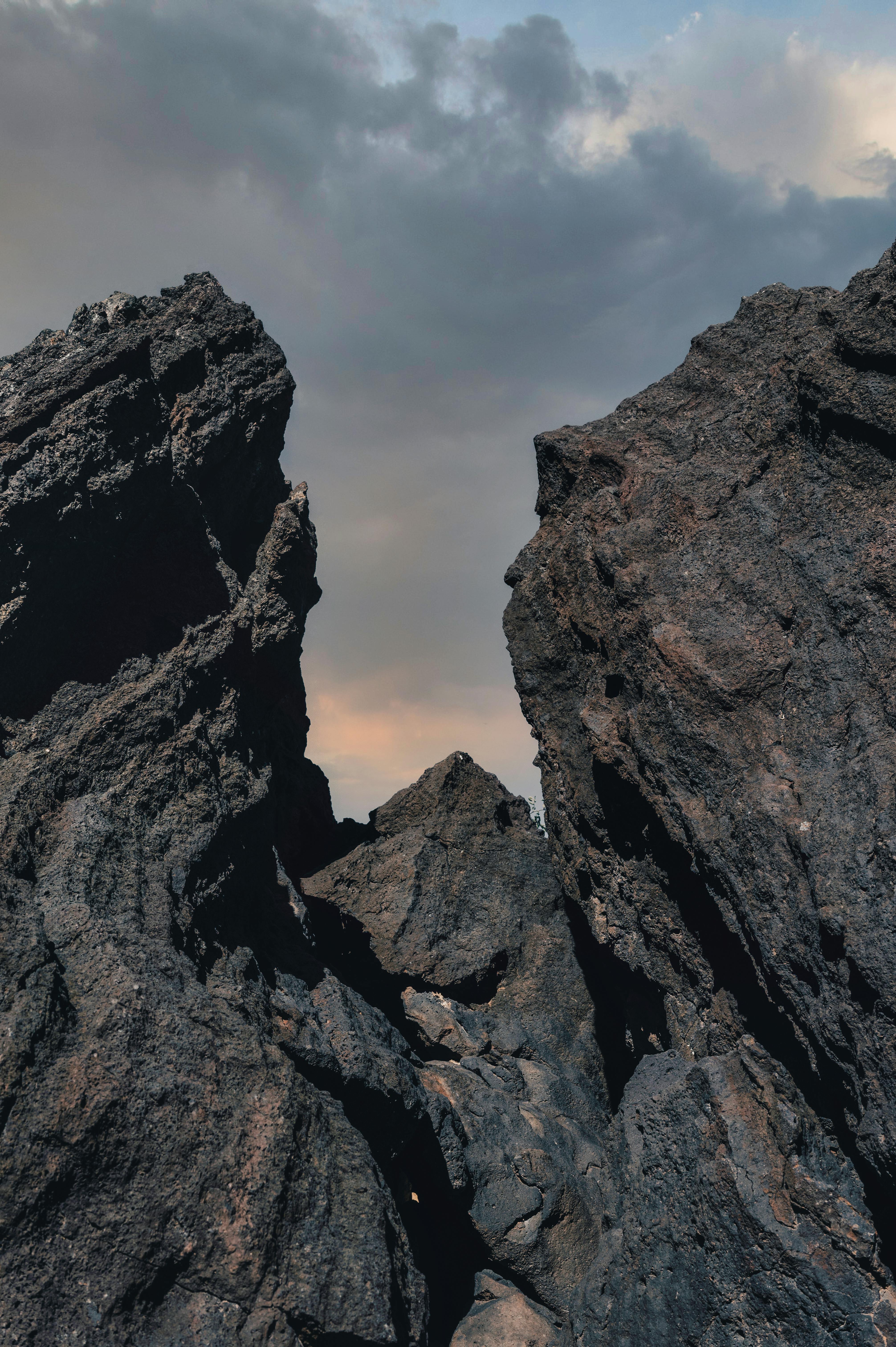 Dramatic rocky formations rise steeply into a cloudy sky, showcasing natural geological beauty.