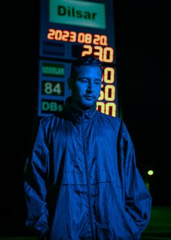 Nighttime urban portrait of a man standing at a gas station in Rioja, Peru.