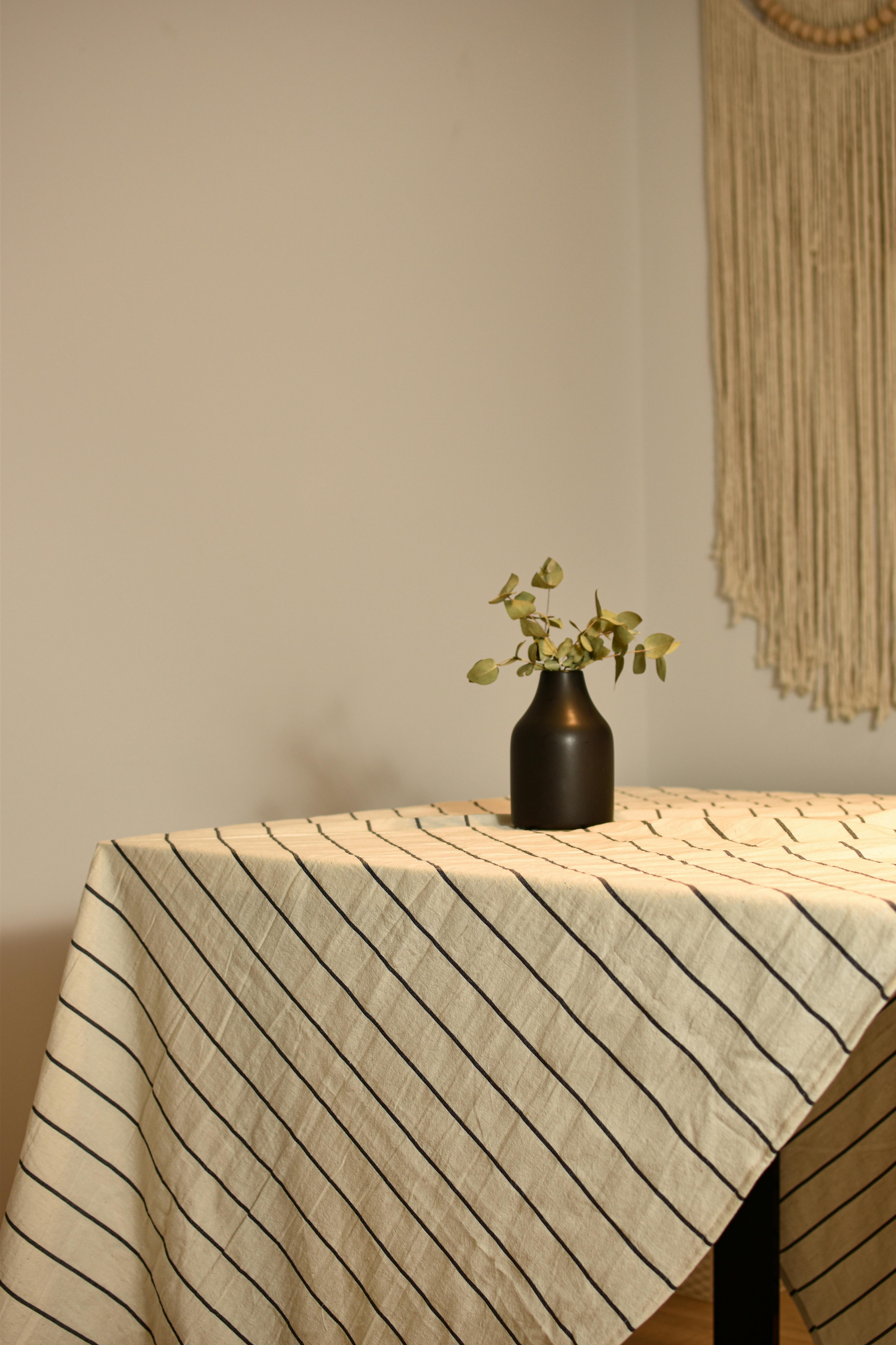 A simple table setting with a striped tablecloth and a small vase in a rustic apartment.
