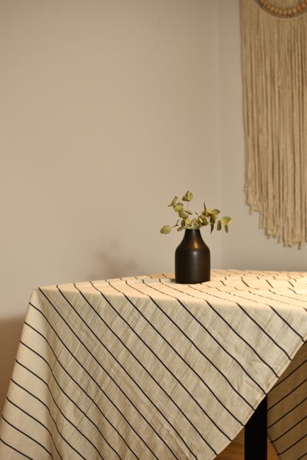 A simple table setting with a striped tablecloth and a small vase in a rustic apartment.