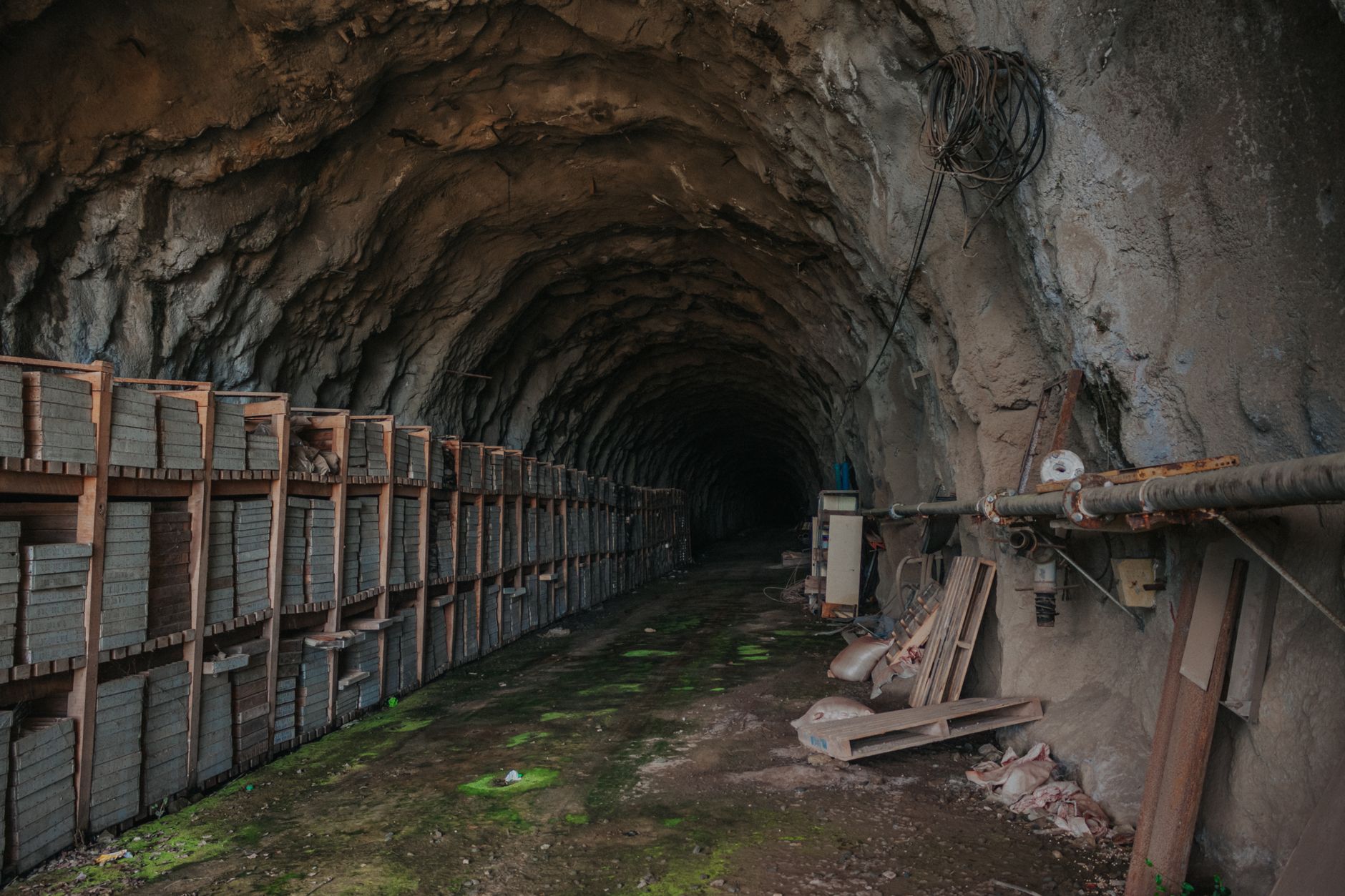 An underground tunnel with stored bricks and industrial equipment, evoking a sense of mystery.