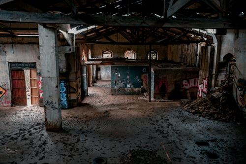 Free Explore the rustic charm of an abandoned warehouse adorned with vibrant graffiti art. Stock Photo