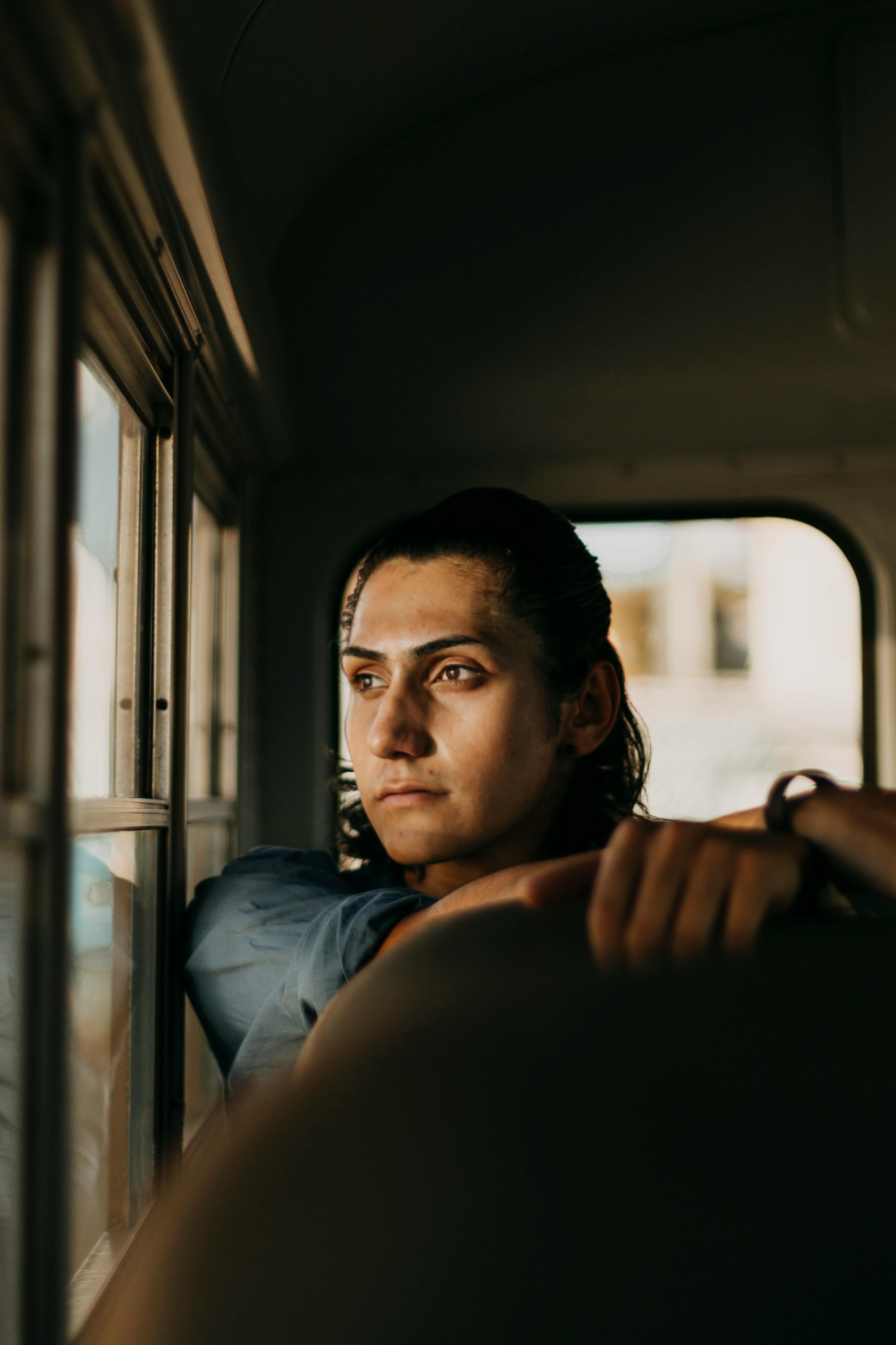 Selective Focus Photography of Man Sitting Inside Vehicle Looking Outside