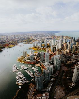 Aerial view of Vancouver, BC showcasing skyscrapers and coastline with vibrant fall colors.
