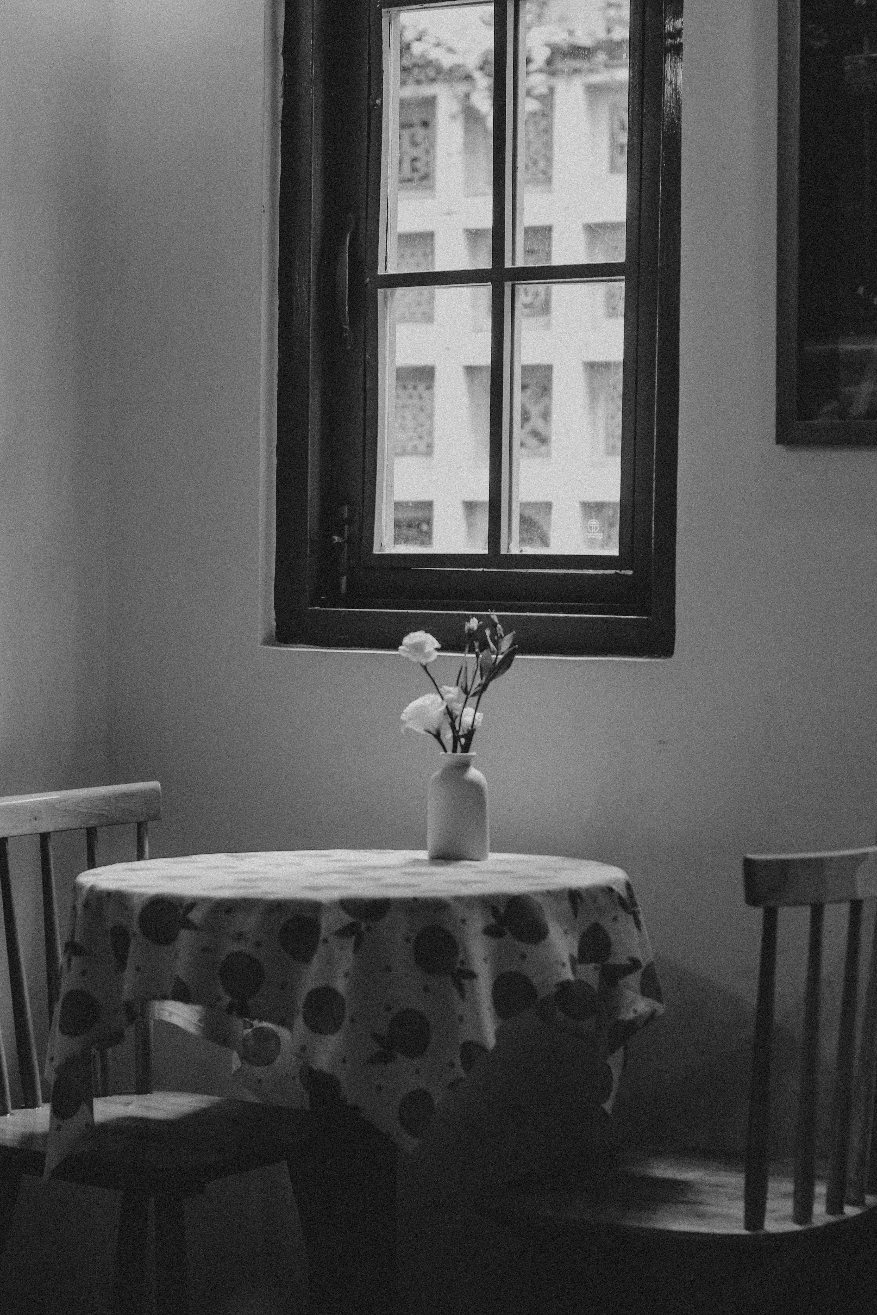 Black and white photo of a cozy table by a window in Ho Chi Minh City, Vietnam.