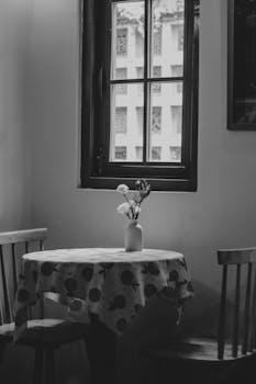 Black and white photo of a cozy table by a window in Ho Chi Minh City, Vietnam.