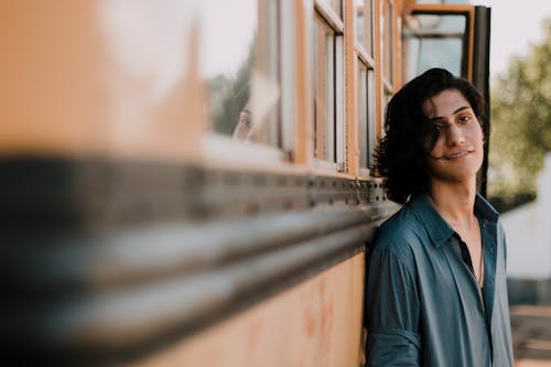 Selective Focus Photography of Man Leaning on School Bus