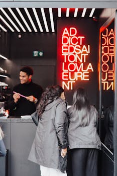 Three people in a neon-lit store with a friendly cashier behind the counter.