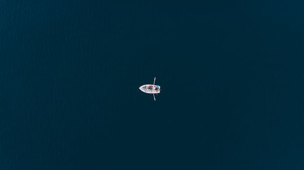 Discover a tranquil aerial view of a solitary rowboat on the open sea near Polignano a Mare.