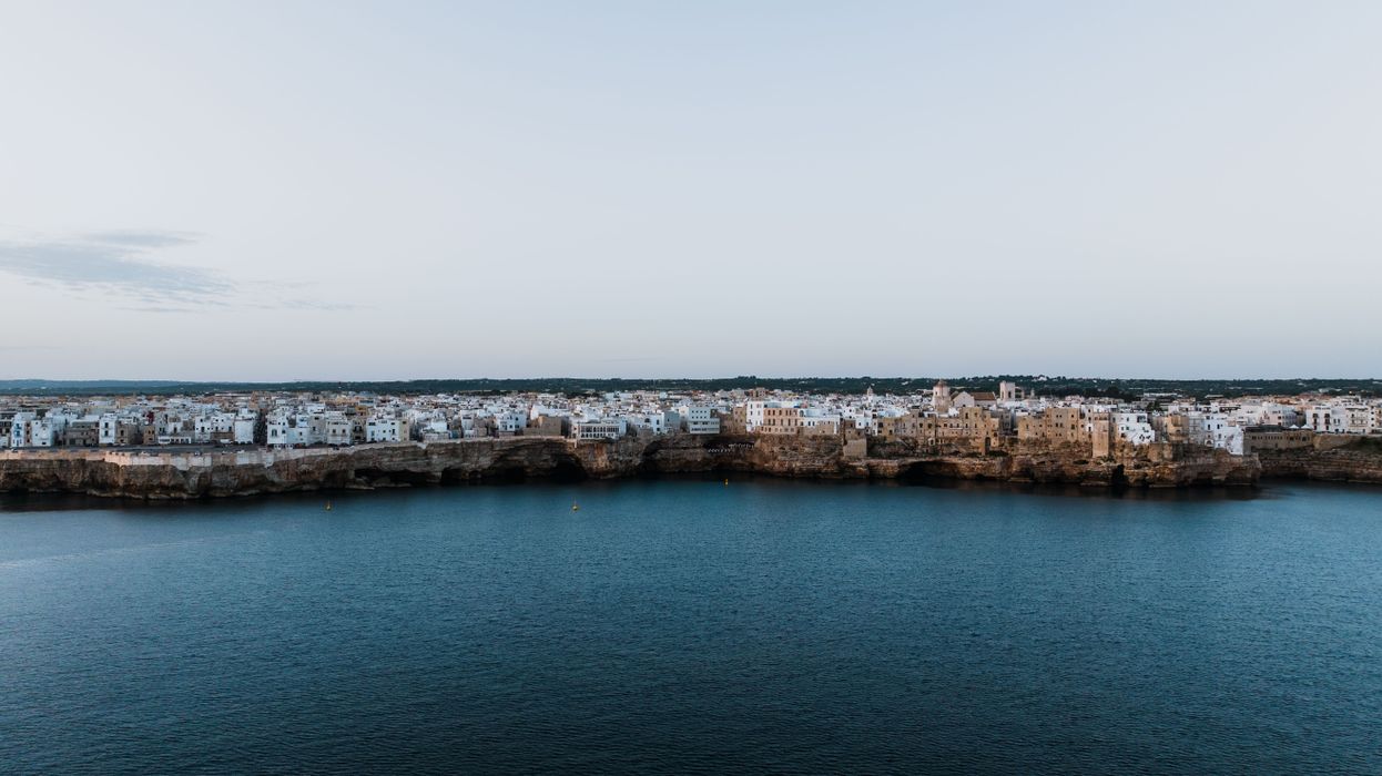 Aerial view of Polignano a Mare coastal town with white buildings perched dramatically on cliffs above the Adriatic Sea in Puglia Italy