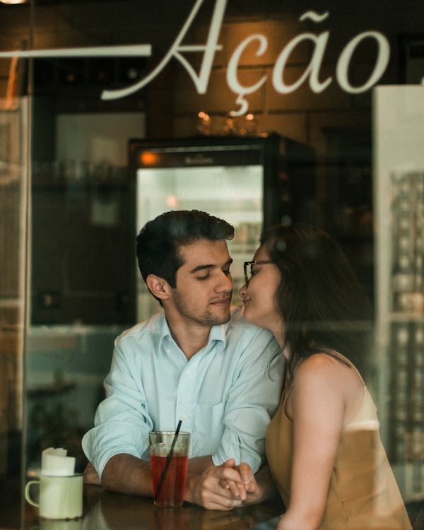 Couple Seated Near Window Holding Hands