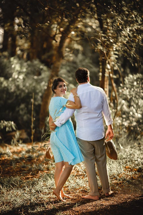 Man Holding Woman on Her Waist While Carrying Shoes