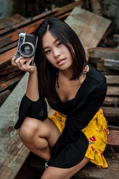 一位时尚的年轻女子在乡村户外拿着老式相机摆姿势