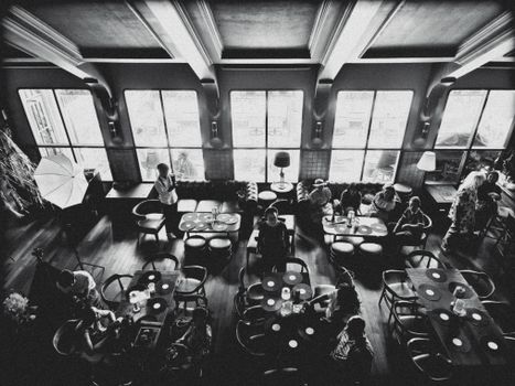 Aerial view of a monochrome cafeteria interior with people dining and socializing.