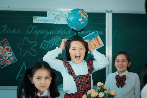 Globe on Head of Laughing Student in Classroom