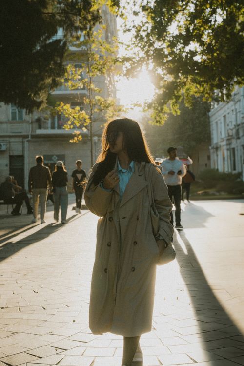 Free A woman in a stylish coat walks through Baku, Azerbaijan, as the sun sets in a serene urban atmosphere. Stock Photo