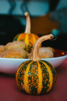 Decorative squashes and buns on a table, perfect for autumn festivities like Thanksgiving or Halloween.