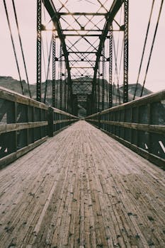 一座以山脉为背景的复古吊桥，铺有木地板和金属结构