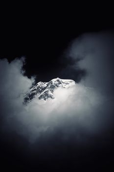 A dramatic view of a snow-covered mountain peak enveloped in dense fog, depicting nature's beauty and mystery.