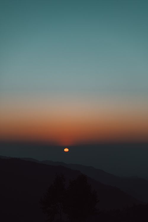 Free A captivating sunset over mountains with rich hues and a calm atmosphere. Stock Photo