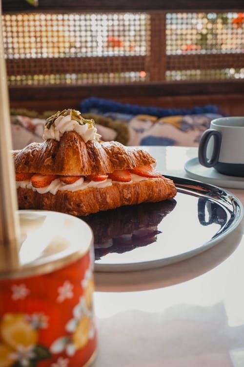 Croissant With Whipped Cream and Strawberries on a Plate