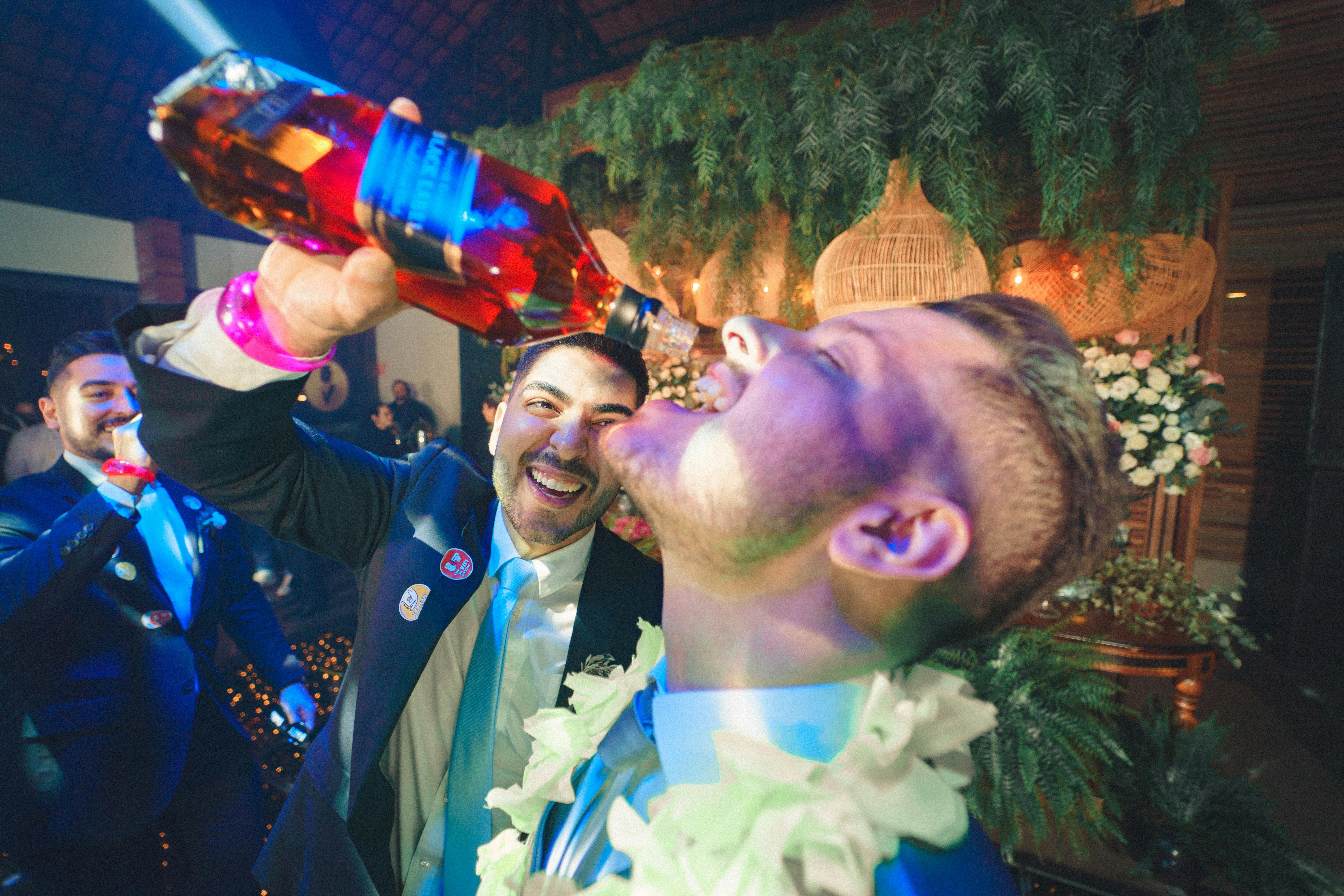 Man Pouring Whiskey from a Bottle Into Another Man Mouth · Free Stock Photo
