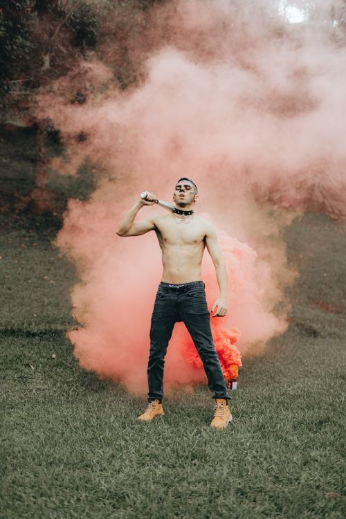 Free Shirtless man with collar standing in a red smoke cloud outdoors. Stock Photo