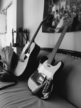 Stylish black and white photo of acoustic and electric guitars resting on a sofa, perfect for music themes.
