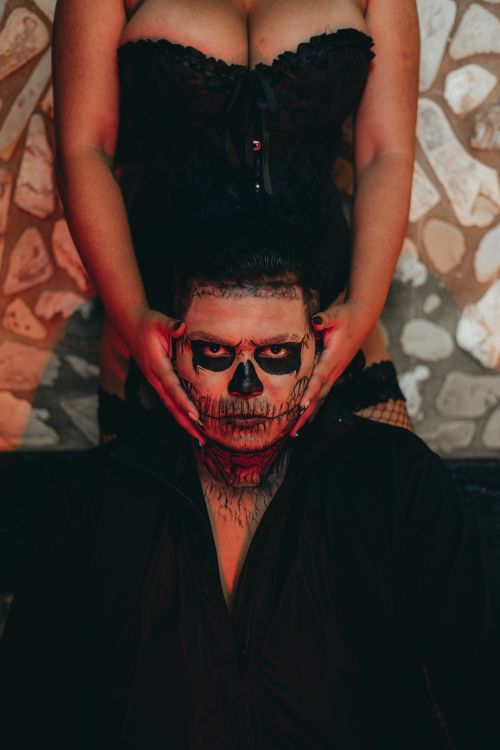 Free A man with a skull painted face held by a woman in a Halloween-themed setting. Stock Photo