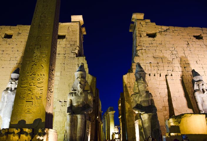 Night view of the illuminated Luxor Temple with ancient statues and hieroglyphs.
