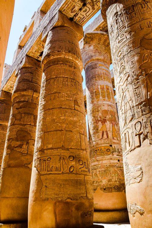 Free Ancient Egyptian temple columns with intricate carvings illuminated by natural daylight. Stock Photo