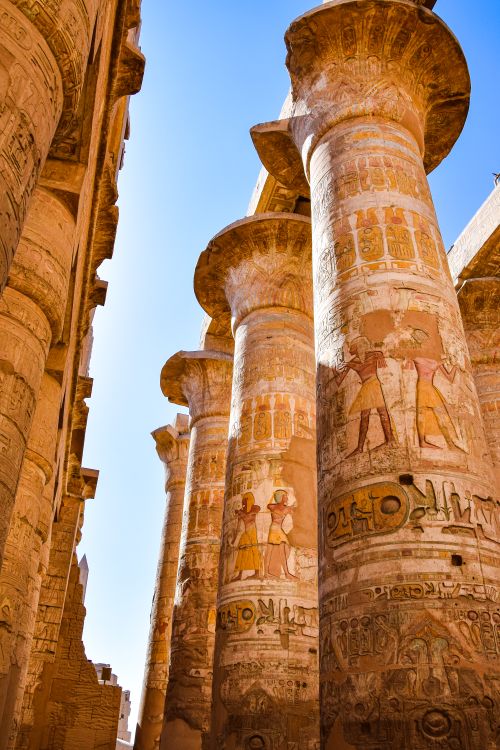 Free Intricate hieroglyphs on the towering columns of Karnak Temple in Luxor, Egypt under clear blue skies. Stock Photo