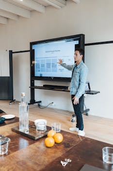 Young man presenting business strategies on a digital screen in an office setting.