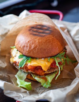 Close-up of a mouthwatering cheeseburger with fresh greens and melted cheese.
