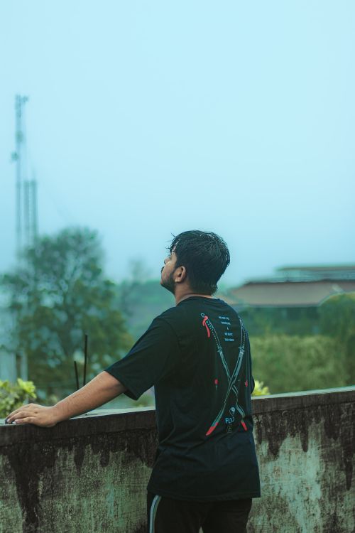 Free A man gazing at the misty landscape from a balcony, evoking a sense of calm and introspection. Stock Photo